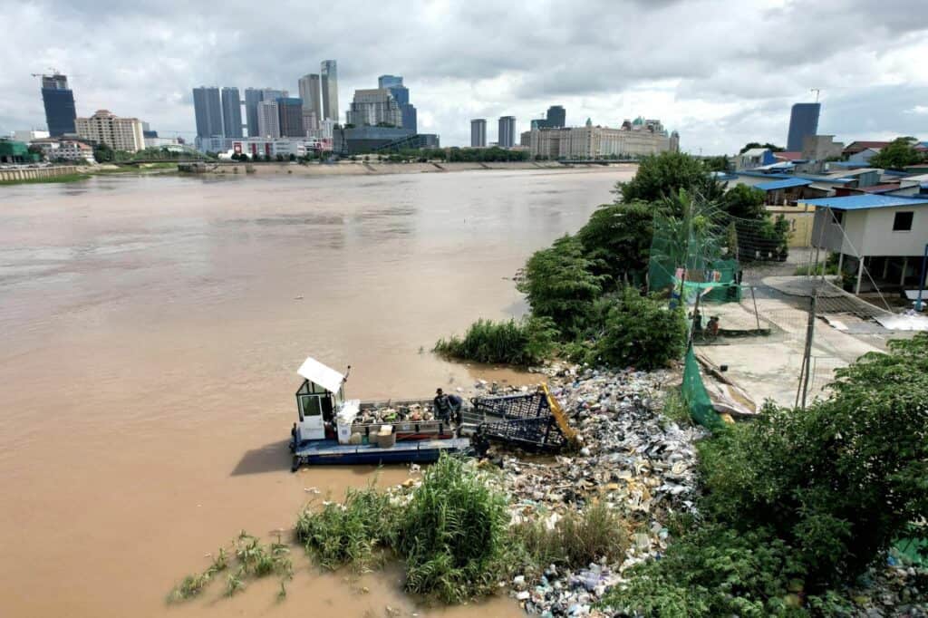 Boat collects waste on river bed on Mekong river in Cambodia